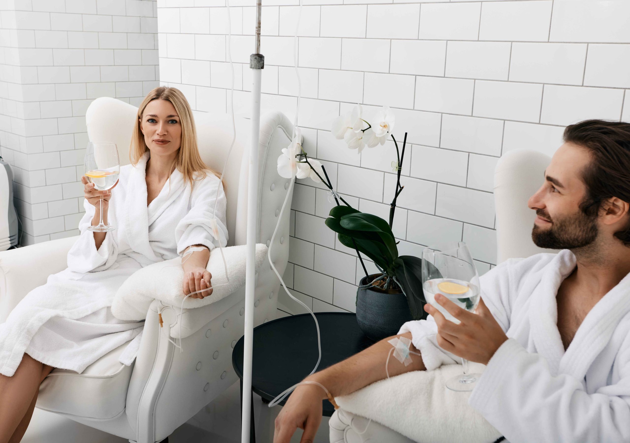 Couple in love during intravenous vitamin therapy. Beautiful woman with her boyfriend with glasses of refreshing drink with lemon in medical clinic for detox their organisms | APEX Performance & Aesthetics in Sandy, UT