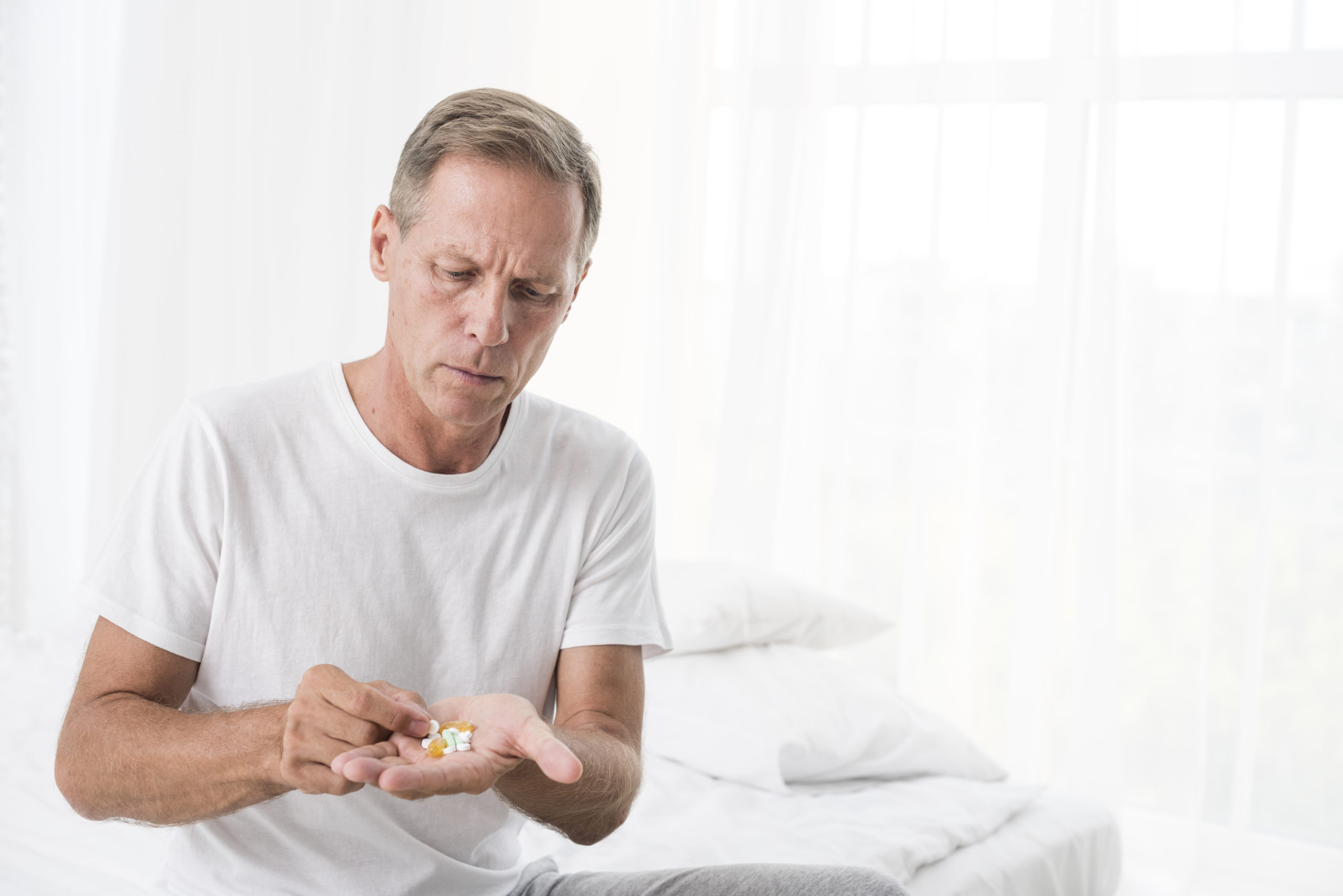 medium-shot-man-with-pills-bedroom