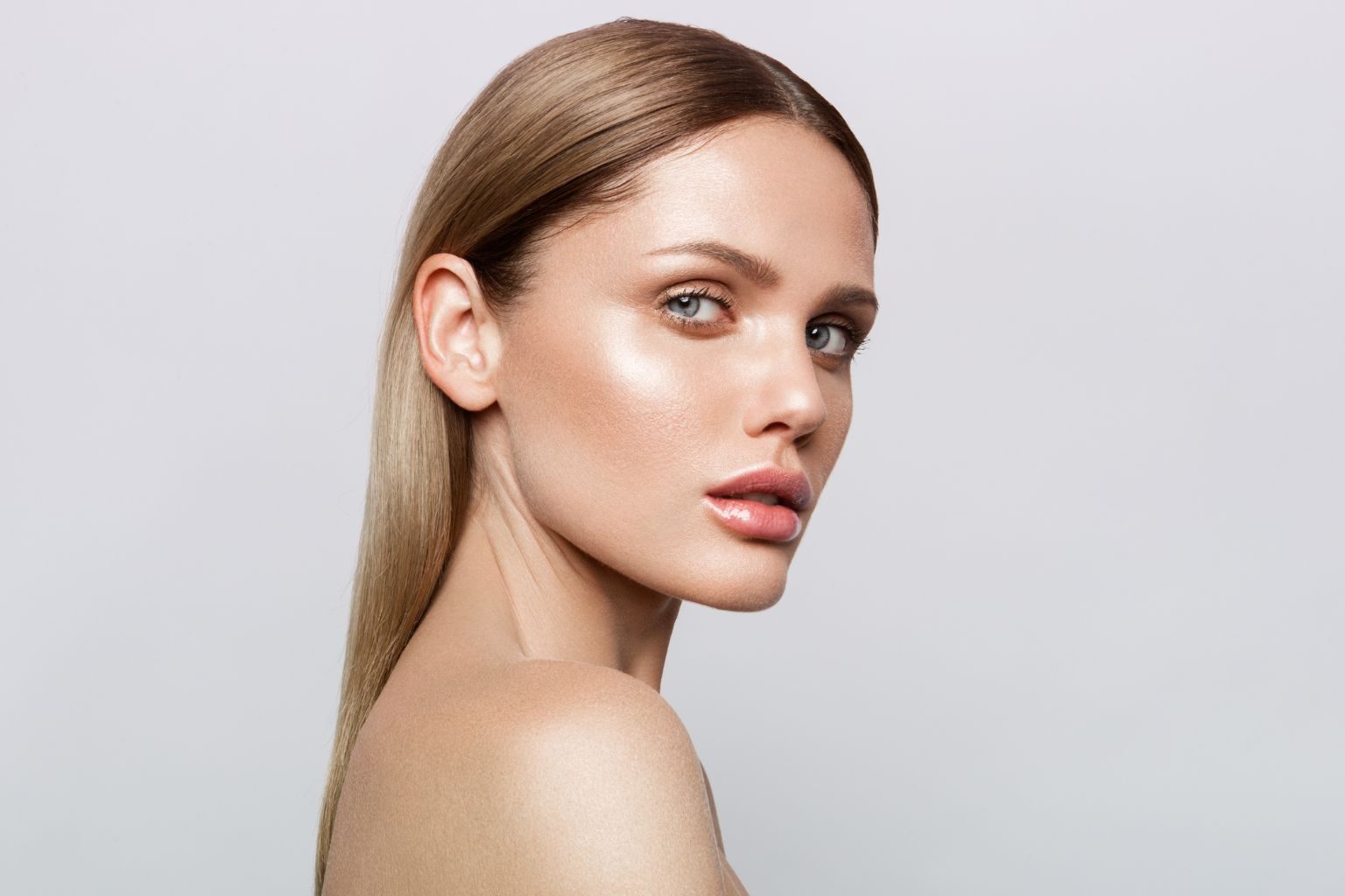 Beauty woman with freckles, thick eyebrows, touching face, using skin care lotion, anti-aging mask with detoxifying nourishing effect. Girl with naked shoulders shows clean and fresh facial skin | APEX Performance & Aesthetics in Sandy, UT