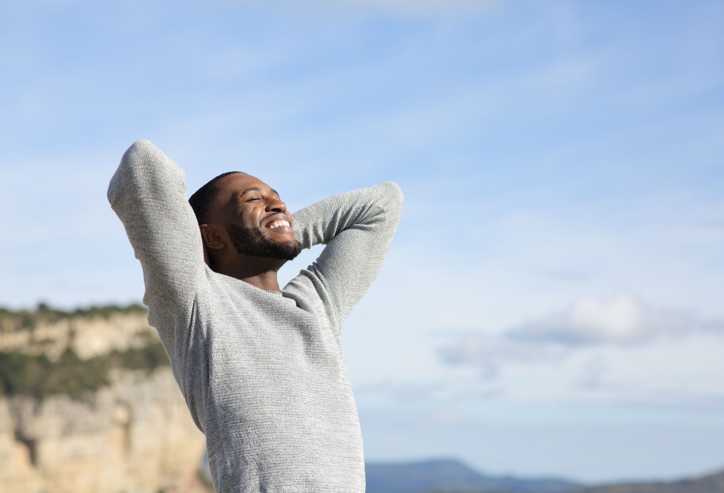 Relaxed man with black skin breathing fresh air with hands on head in the mountain | APEX Performance & Aesthetics in Sandy, UT
