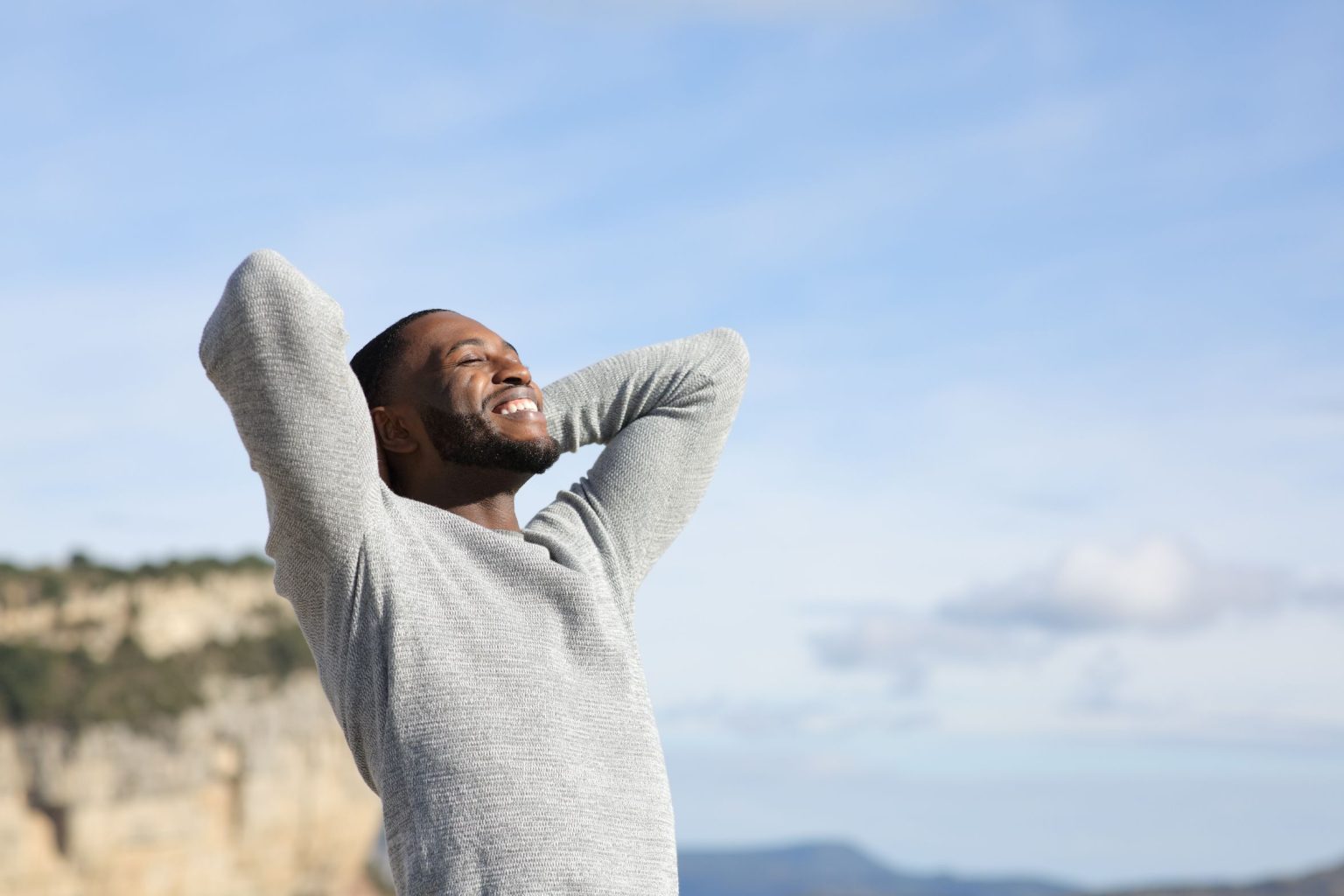 Relaxed man with black skin breathing fresh air with hands on head in the mountain | APEX Performance & Aesthetics in Sandy, UT Relaxed man with black skin breathing fresh air with hands on head in the mountain | APEX Performance & Aesthetics in Sandy, UT